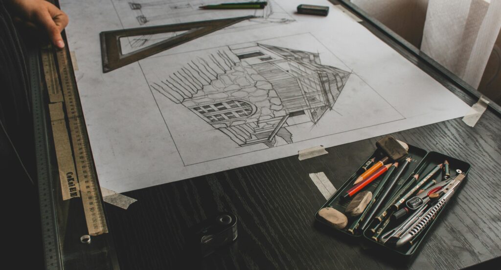Close-up of an architectural sketch with drafting tools on a desk.