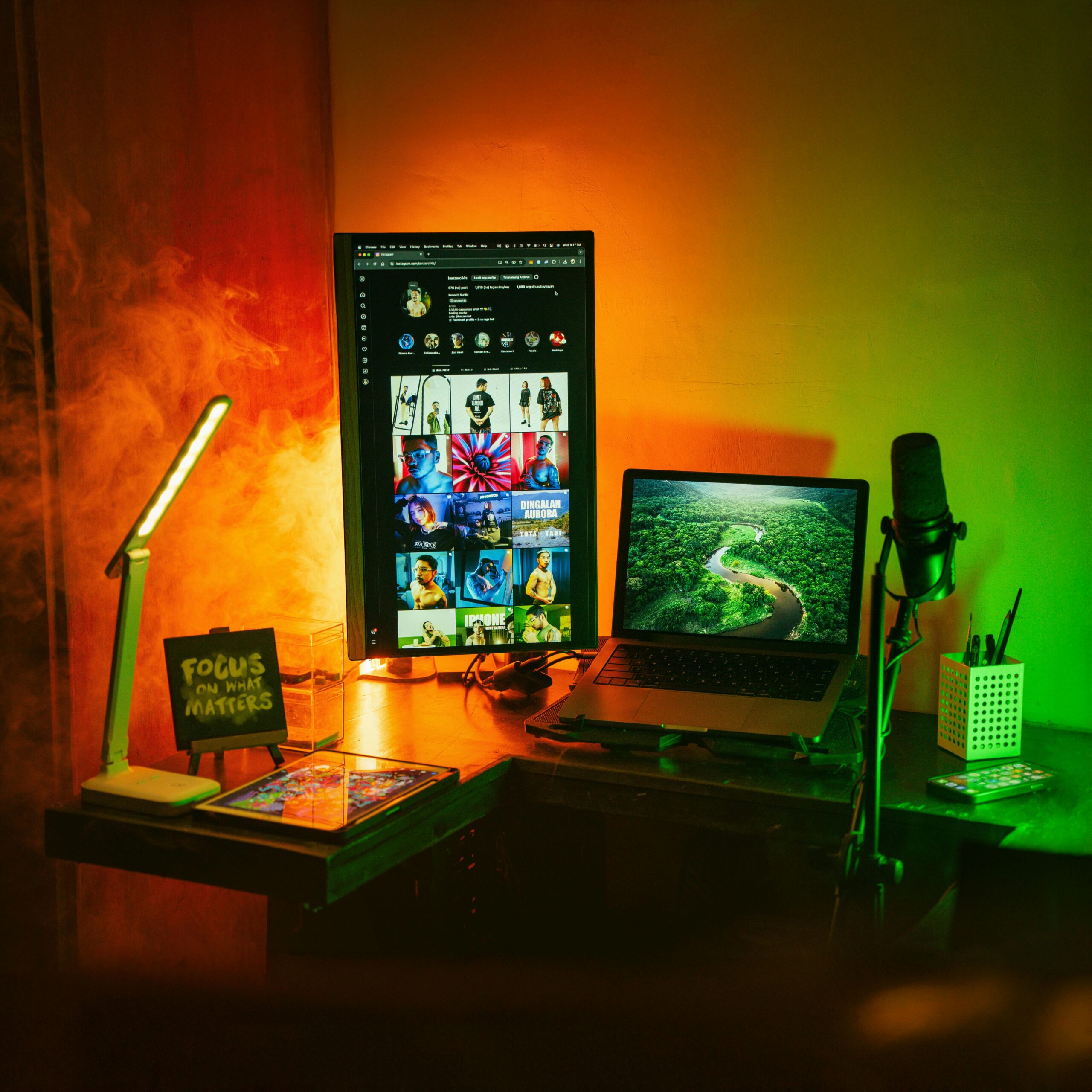 A vibrant home office space with a vertical monitor, laptop, and creative lighting.