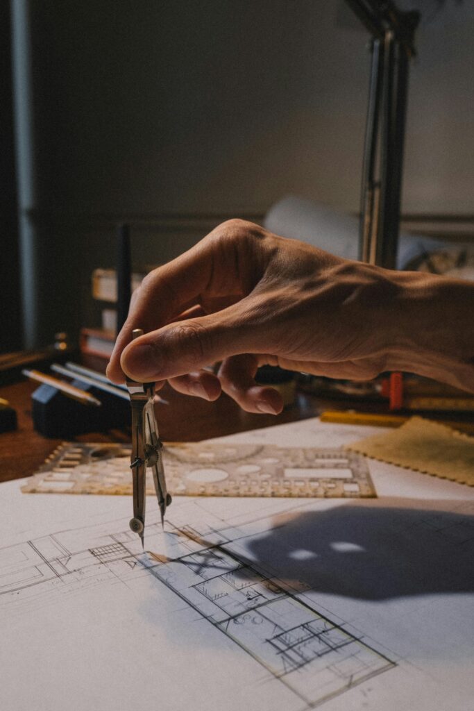 Close-up of an architect's hand using a compass on a blueprint, showcasing detailed architectural work in progress.